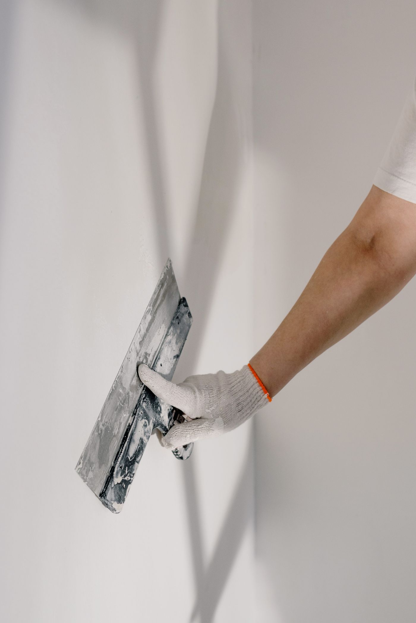Trowel smoothing compound on a wall, Pexels.